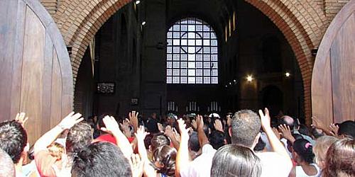 Enquanto padres rezavam, muitos erguiam as mãos perto das portas de entrada do templo