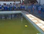 Crianças observam piscina que não pode ser utilizada