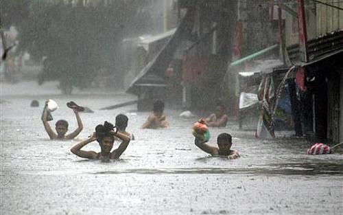 Moradores tentam percorrer uma rua inundada em Manila, nas Filipinas, após passagem de tufão