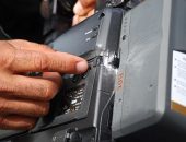 Repórter cinematográfico exibe equipamento danificado após ser atingido por estilhaços