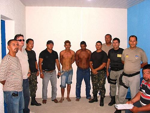 Os dois homens presos (ao centro) são acusados em vários crimes