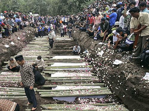 Parentes jogam flores durante enterro de vítimas do vulcão, em Umbulharjo