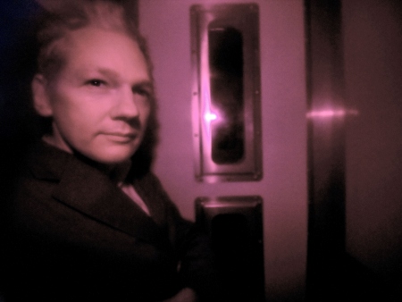 Fundador do WikiLeaks, Julian Assange, olha por janela de camburão coberta por filme escuro durante chegada a tribunal na Inglaterra, nesta terça (14)