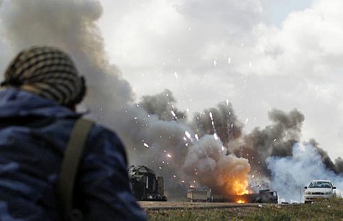 Combatente rebelde observa veículo em chamas após ataque da coalizão internacional contra as forças de Muammar Kadhafi, neste domingo (20)