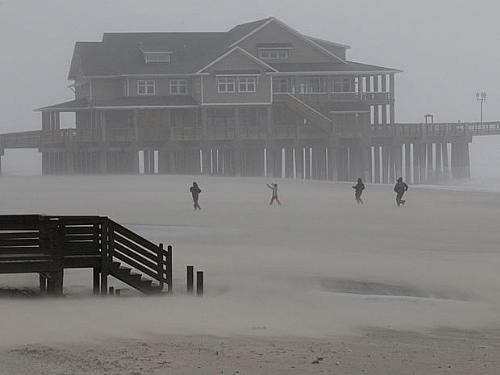Pessoas caminham por Nags Head, no litoral da Carolina do Norte, mesmo com os efeitos do furacão Irene