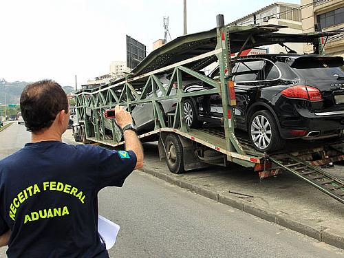 Agente da Receita Federal fotografa carros importados apreendidos em operação da Polícia Federal na Barra da Tijuca, Zona Oeste do Rio