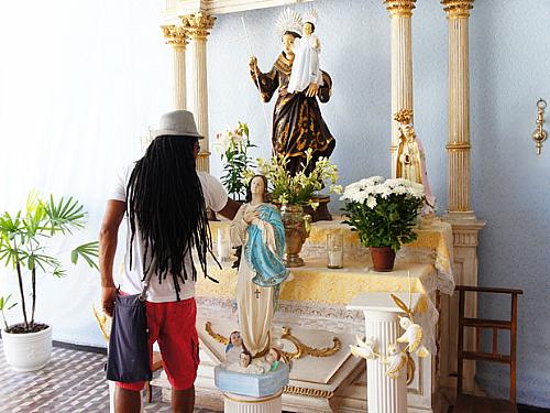 Carlinhos Brown ora diante de imagem de Santo Antônio, no Candyall Guetho Square, antes de viajar para os EUA