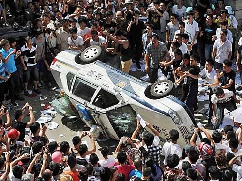 Manifestantes chineses viram carro da polícia em Qidong, durante protesto contra fábrica que pretendia jogar resíduos poluentes e contaminar água na região.