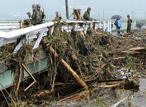 Militares observam árvores arrastadas pela chuva em Aso, na província japonesa de Kumamoto, neste sábado (14)