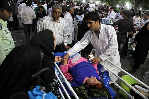 Médico atende mulher ferida do lado de fora de hospital em Ahar, cidade iraniana afetada por terremoto neste sábado (11)