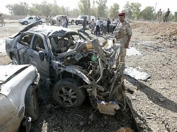 Soldado iraquiano inspeciona a explosão que veio de um carro, a 15 km da cidade de Kirkuk, neste domingo (9)