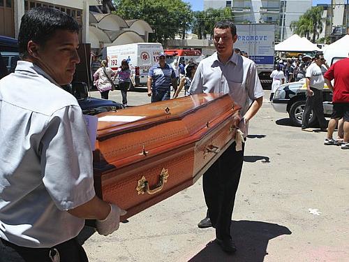 Funcionários de funerária carregam caixão com corpo de vítima de incêndio em Santa Maria