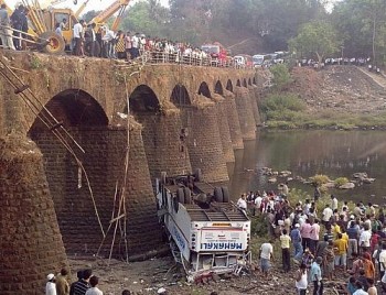 Resgatistas e passantes observam destroços de ônibus que caiu de ponte no distrito de Ratnagiri, no estado indiano de Maharashtra, nesta terça-feira (19)