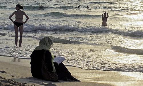 Mulher lê sentada na areia em Dubai, em foto tirada em setembro do 2012. Emirados Árabes Unidos aprovou recentemente a proibição de 'trajes de banho reveladores' em praias públicas da confederação