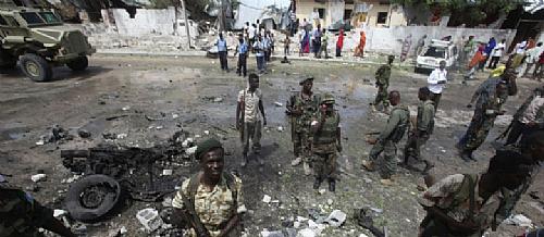 Soldados do governo somali permanecem na cena do atentado suicida contra o complexo da ONU em Mogadíscio que matou cinco pessoas