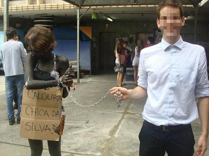 Jovem aparece acorrentada, com o corpo pintado e carregando uma placa na qual se lê Caloura Chica da Silva