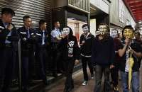 Manifestantes usando máscaras de Guy Fawkes passam por policiais em uma rua ocupada por ativistas em Hong Kong (5/11)