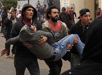 Manifestantes ajudam ferido após pessoas pró-governo jogarem pedra em opositores no Cairo