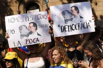 Manifestantes pela independência da Catalunha exibem cartazes com imagem do chefe de governo espanhol, Mariano Rajoy, beijando o ditador Franco, durante protesto nesta sexta-feira (29) em Barcelona