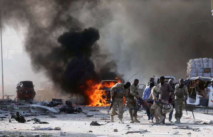 Pessoas carregam o corpo de uma vítima de explosão em Mogadíscio, capital da Somália,neste sábado (14) 