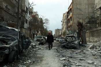 Sírio caminha entre prédios destruídos em Duma, cidade de Guta Oriental, neste domingo (25), oito dias após a intensificação do conflito na região
